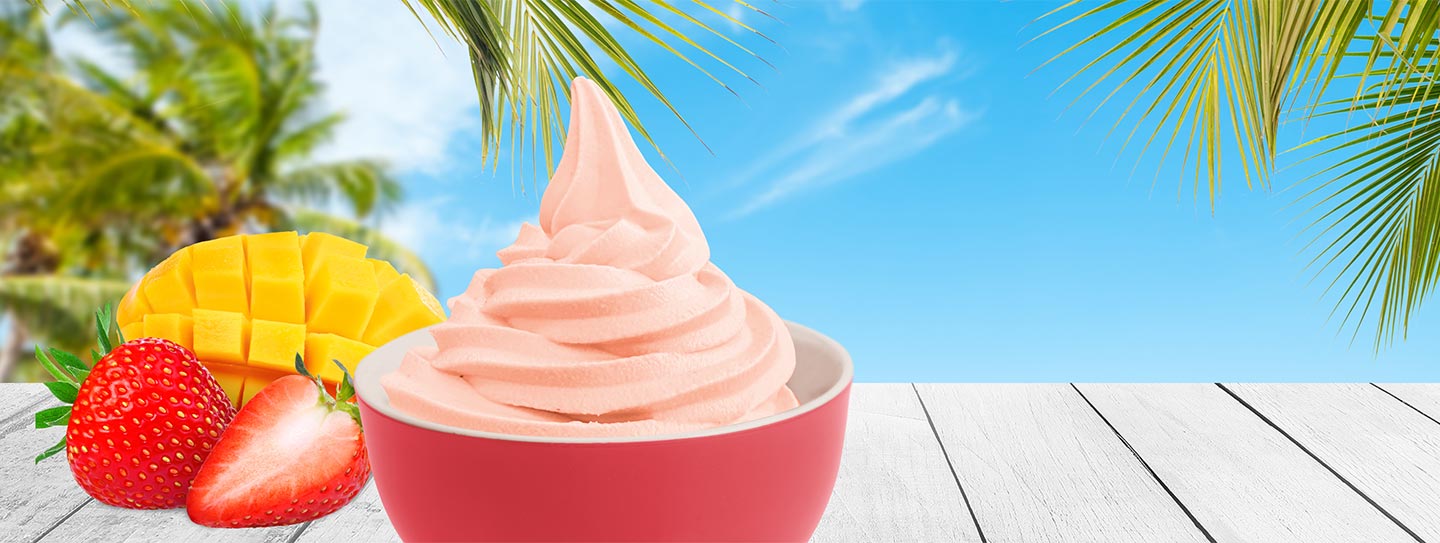 A cup of frozen yogurt alongside mango and strawberries.