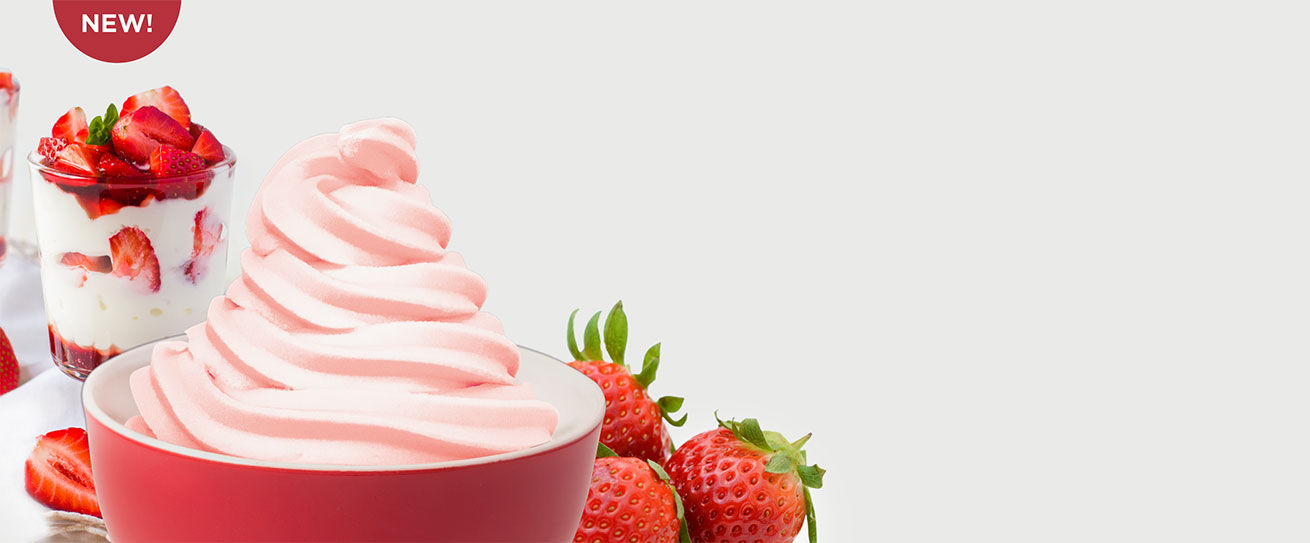 A cup of frozen yogurt alongside fresh strawberries