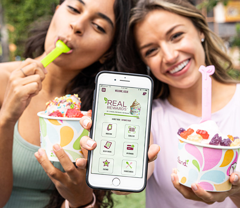 Two people using the Yogurtland Real Rewards app.